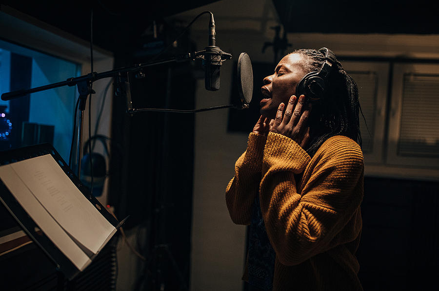 Black female singer singing into microphone in recording studio #1 Photograph by South_agency