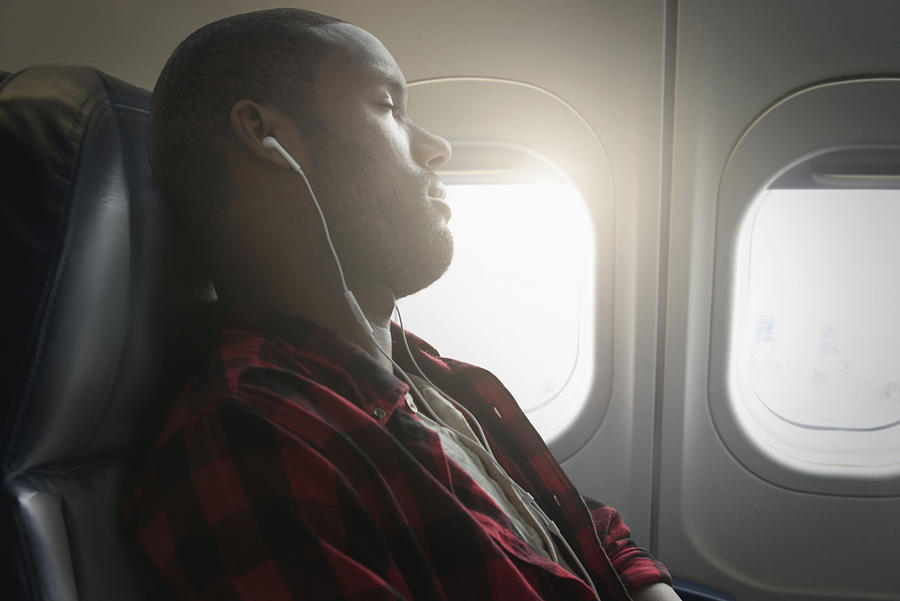 Black man listening to earbuds on airplane #1 Photograph by Jose Luis Pelaez Inc