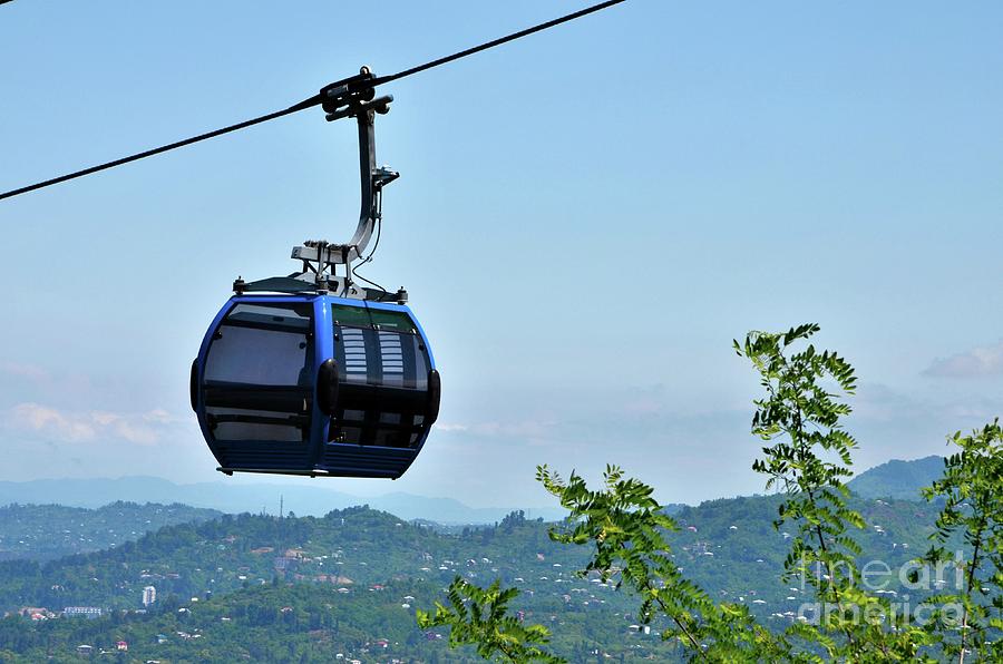 Architecture Photograph - Blue tinted glasses cable car moves over green forest area and city buildings Batumi Georgia #3 by Imran Ahmed