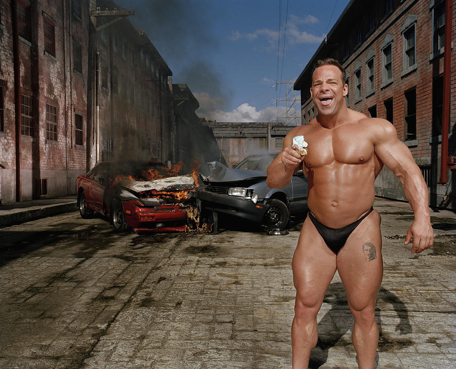 Bodybuilder eating ice cream cone, car collision in background #1 Photograph by Matthias Clamer