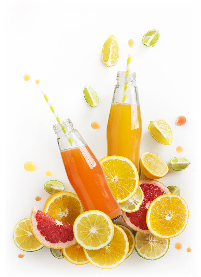 Bottled citrus juice with fresh citrus slices on white background. Juice flowing or splashing out from the bottle. Refreshing citrus juice design element. #1 Photograph by Twomeows