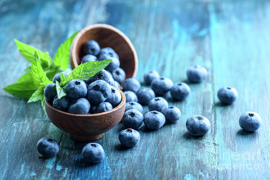 Bowl of fresh blueberries on blue rustic wooden table closeup. #1 Photograph by Jelena Jovanovic