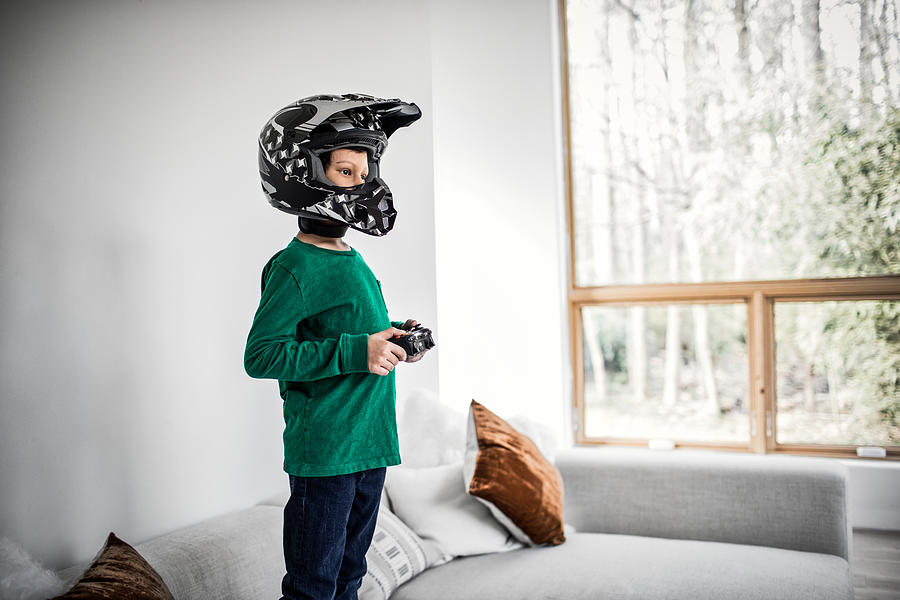Boy playing video games and wearing motorcycle helmet #1 Photograph by MoMo Productions