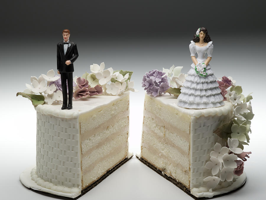 Bride and groom figurines standing on two separated slices of wedding cake #1 Photograph by Jeffrey Hamilton