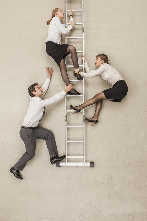 Business people climbing ladder in office #1 Photograph by Westend61