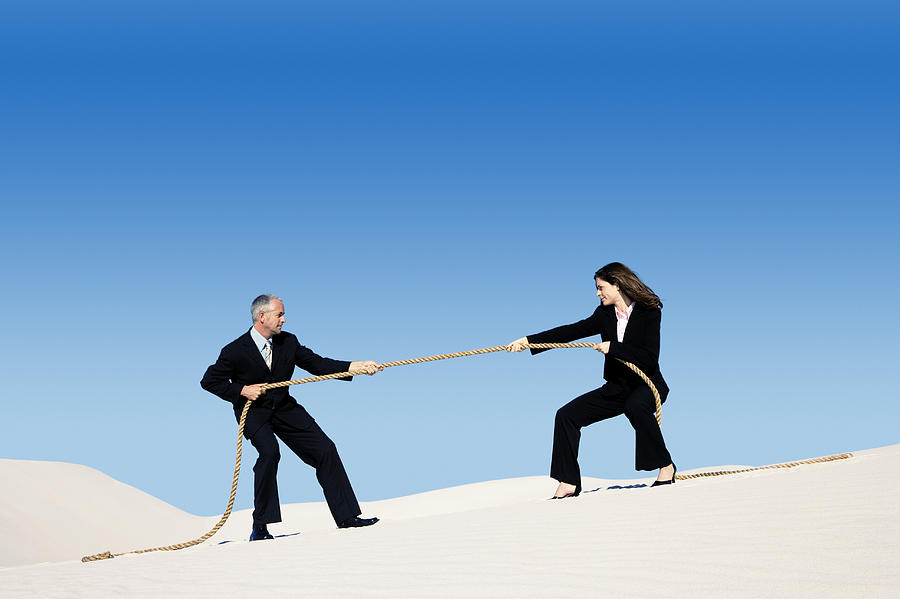 Businessman and Businesswoman Playing Tug of War in a Desert #1 Photograph by John Cumming