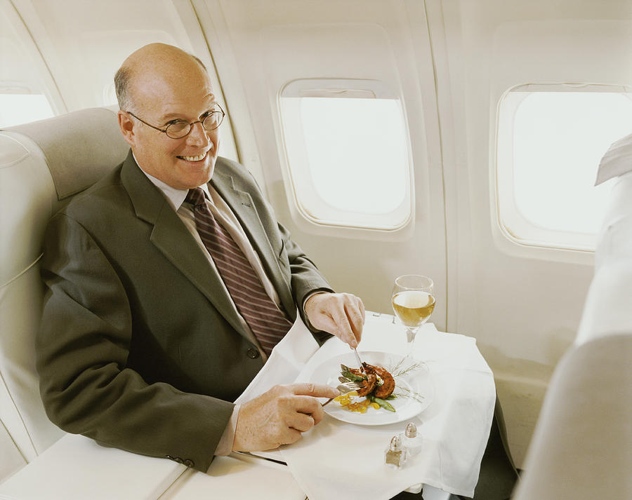 Businessman Sitting in an Aircraft Eating a Meal #1 Photograph by Digital Vision.