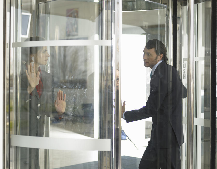 Businesspeople in revolving door #1 Photograph by John Howard