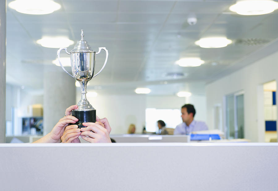 Businesswoman holding trophy over office cubicle #1 Photograph by Jacobs Stock Photography Ltd