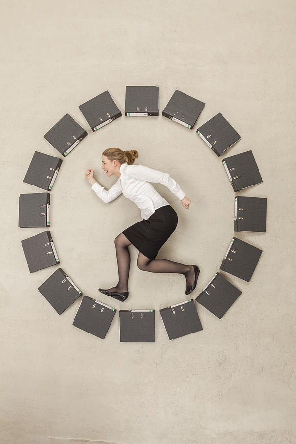 Businesswoman inside circle of files forming clock #1 Photograph by Westend61