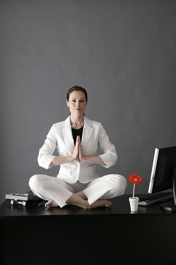 Businesswoman meditating on desk #1 Photograph by Comstock Images