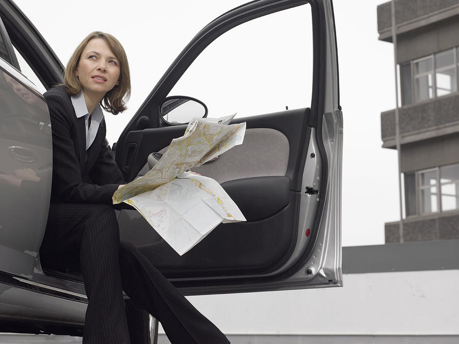 Businesswoman Sitting in Her Car With a Map #1 Photograph by Digital Vision.