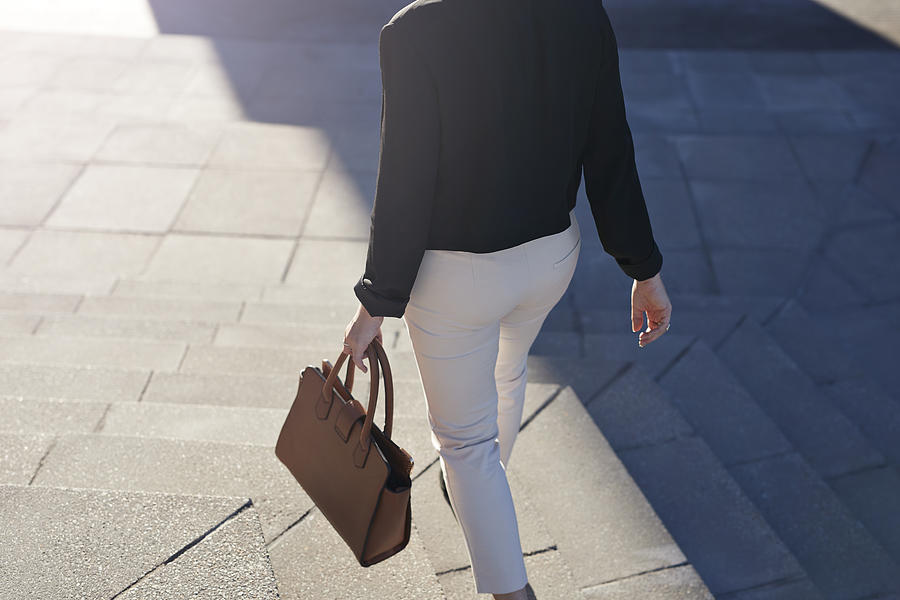 Businesswoman walking on staircase with bag #1 Photograph by Klaus Vedfelt