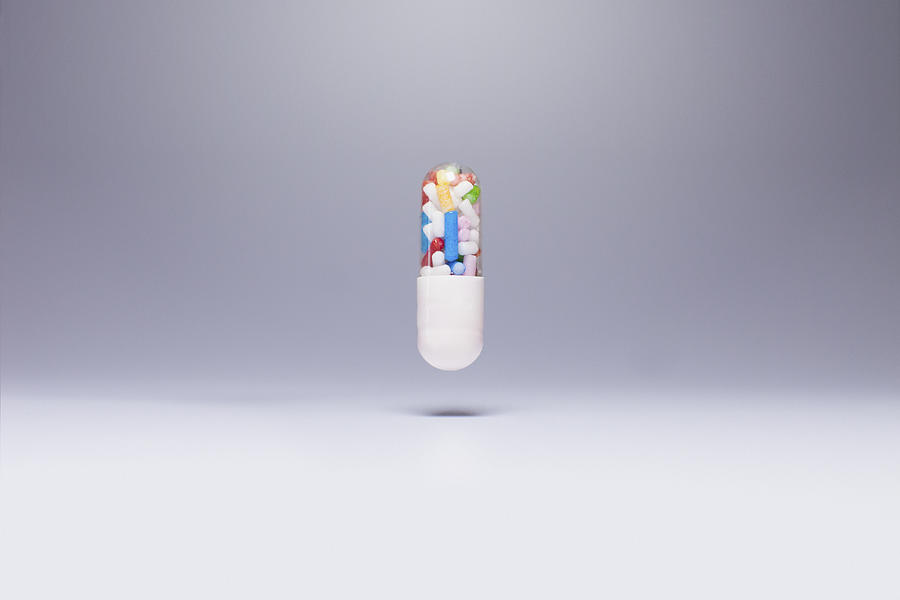 Capsule containing sprinkles in mid-air against gray background #1 Photograph by Ralf Hiemisch