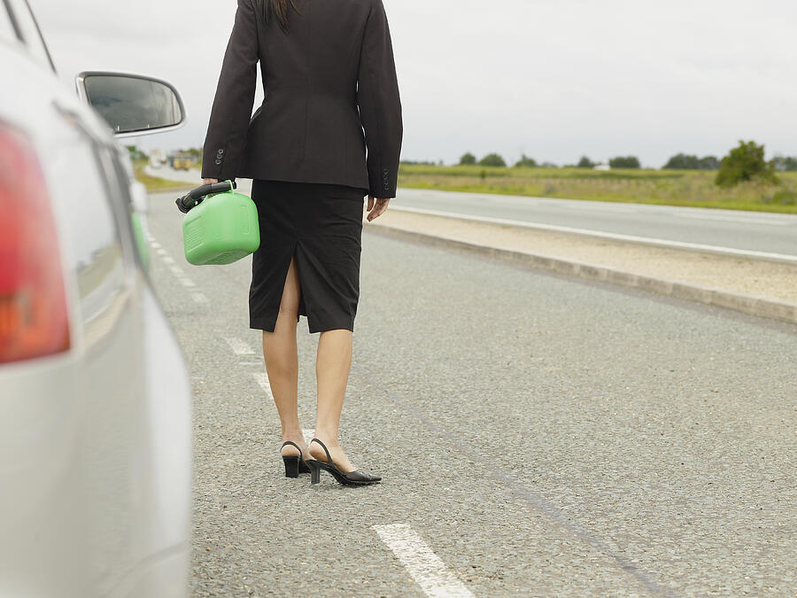 Caucasian businesswoman carrying gasoline can on rural road #1 Photograph by Jacobs Stock Photography Ltd