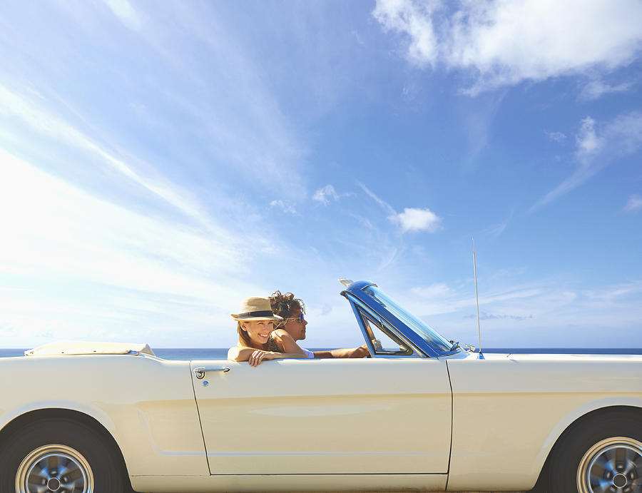 Caucasian couple driving convertible under blue sky #1 Photograph by Colin Anderson Productions pty ltd