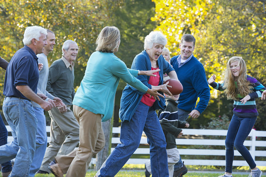 Caucasian family playing football together outdoors #1 Photograph by Ariel Skelley