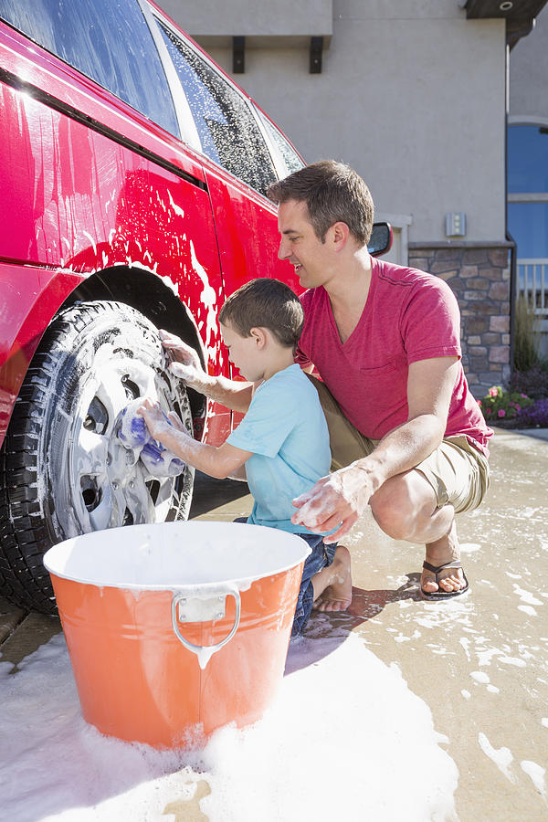 Caucasian father and son washing car in driveway #1 Photograph by Mike Kemp