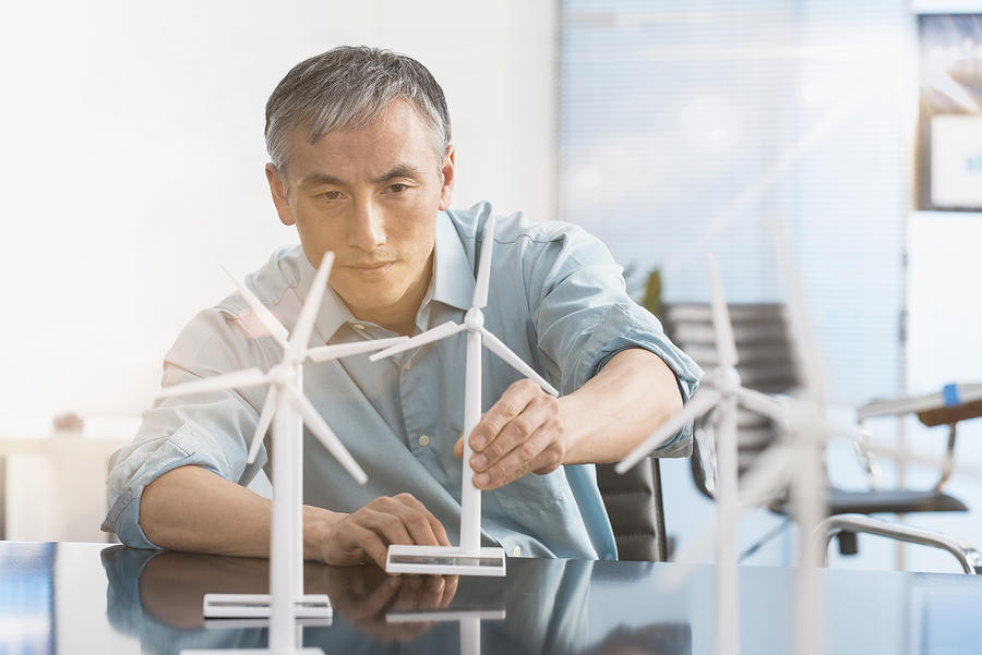 Chinese engineer examining model wind turbines in office #1 Photograph by Jose Luis Pelaez Inc