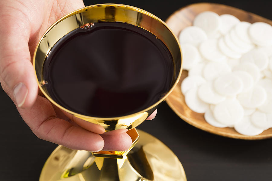 Christian holy communion, mans hand holding gold chalice with wine, communion wafer on plate #1 Photograph by Vstock