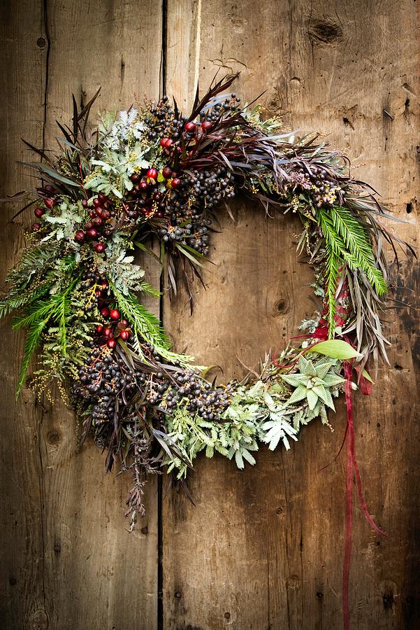 Christmas wreath with foliage and berries on wooden door #1 Photograph by Lindsay Upson