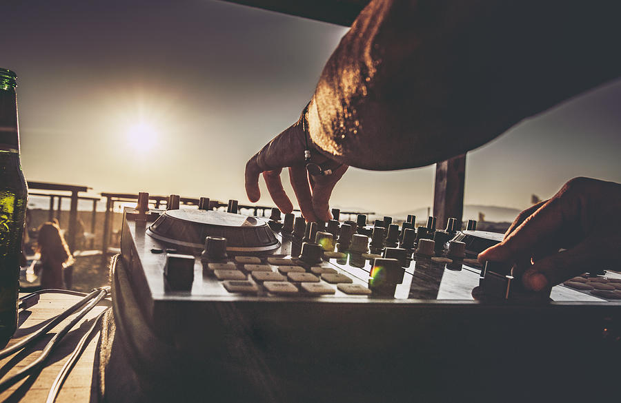 Close up of a DJ playing music on the beach at sunset. #1 Photograph by Skynesher