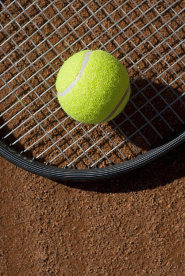 Close-up of a tennis ball on a racket in a court #1 Photograph by Glowimages