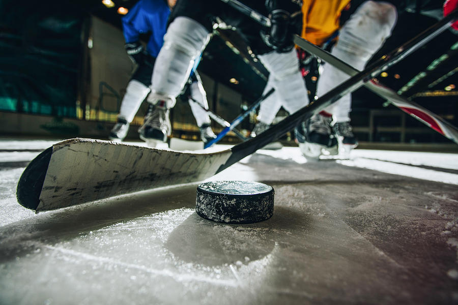 Close up of ice hockey puck and stick during a match. Photograph by Skynesher
