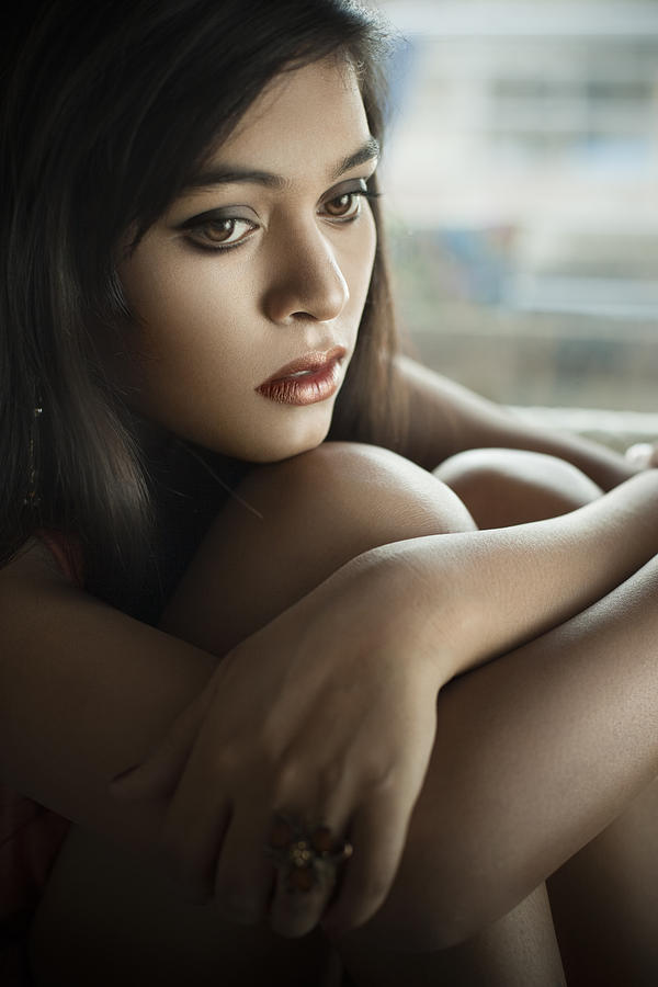 Close-up of serene Sad Asian teenager girl sitting near window. #1 Photograph by Gawrav
