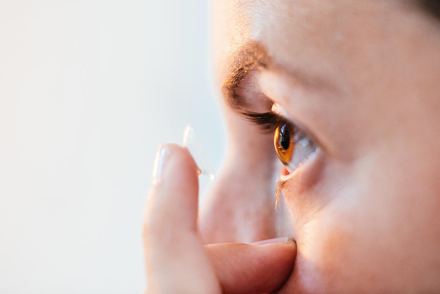 Close up of woman putting in contact lens. #1 Photograph by Guido Mieth