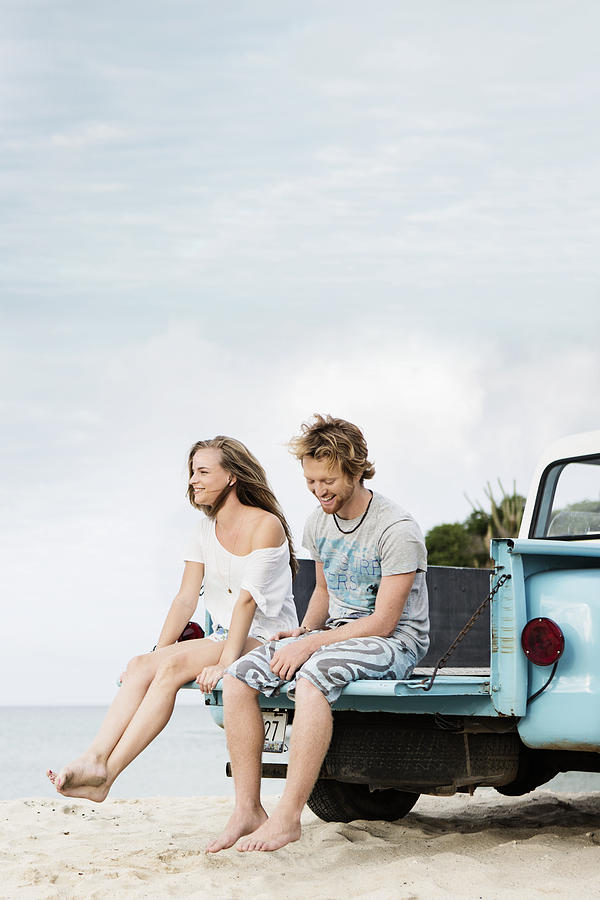 Couple sitting on tailgate of truck on beach #1 Photograph by Felix Wirth
