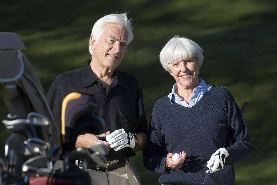 Couple with golf clubs #1 Photograph by Comstock Images