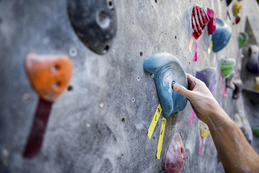 Cropped image of athlete holding rock on climbing wall #1 Photograph by Cavan Images