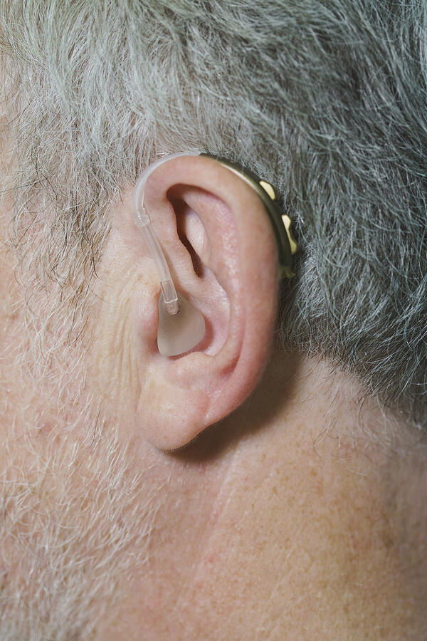 Cropped image of man wearing hearing aid #1 Photograph by Halfdark