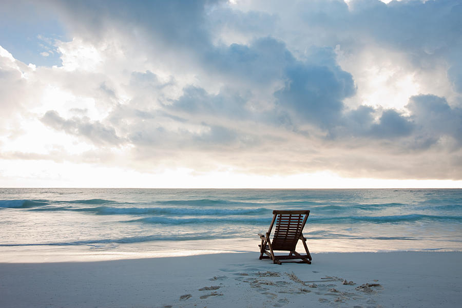 Deck chair on sandy beach at waters edge #1 Photograph by Image Source