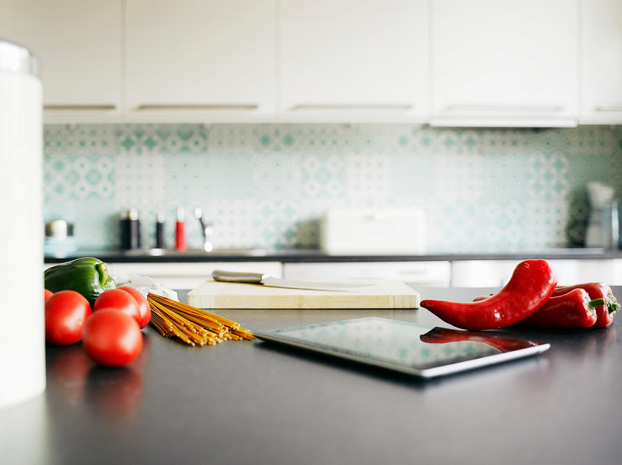 Digital tablet, red peppers and tomatoes on kitchen counter #1 Photograph by Soren Hald