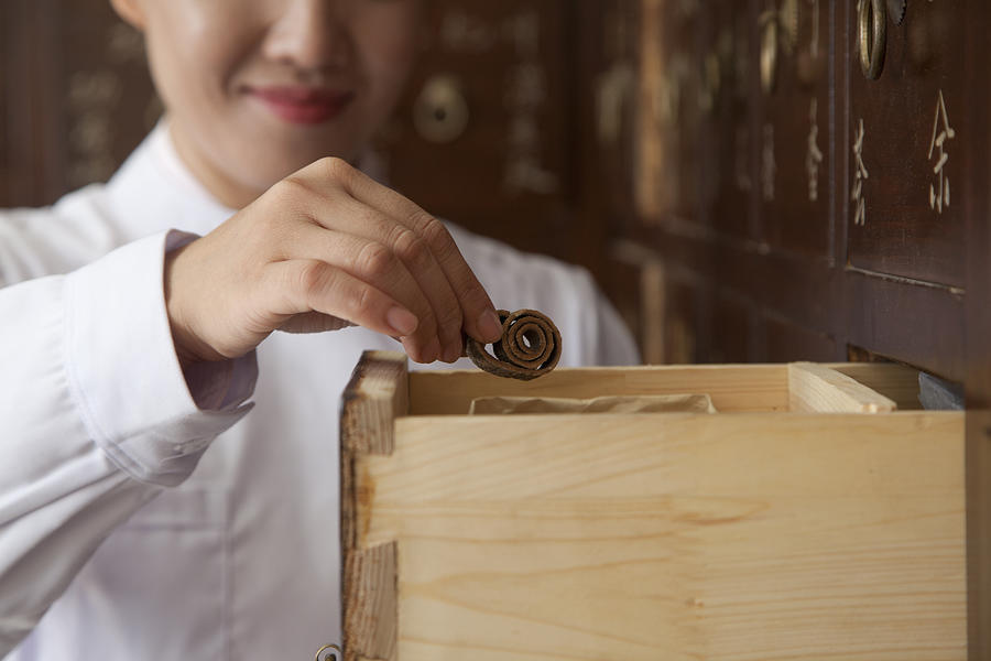 Doctor Taking Herb Used for Traditional Chinese Medicine Out of a Drawer #1 Photograph by XiXinXing