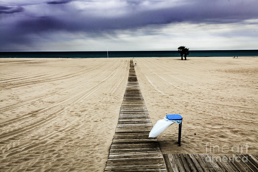 Empty beach on an overcast windy day with rubbish bin #1 Photograph by Peter Noyce