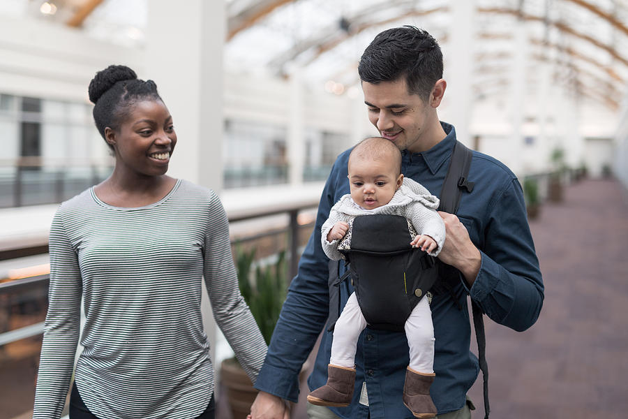 Ethnic Mom and Dad take their newborn daughter to the mall #1 Photograph by FatCamera