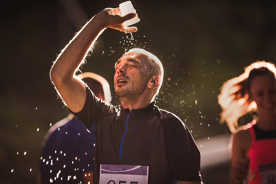 Exhausted runner pouring water on his head during marathon race in nature. #1 Photograph by Skynesher
