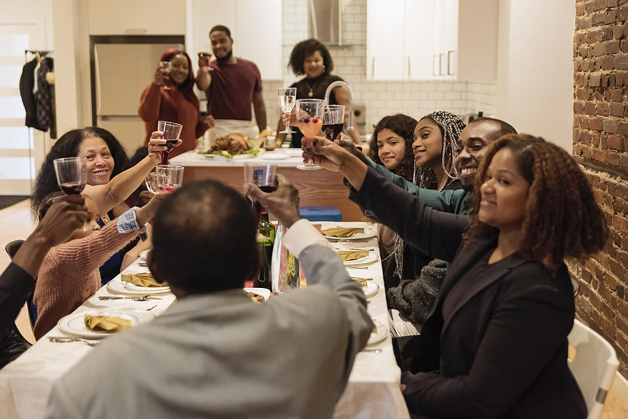 Family cheering enjoying Thanksgiving dinner. #1 Photograph by Martinedoucet
