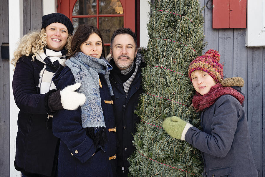 Family portrait with freshly cut Christmas tree in front of house outdoors. #1 Photograph by Martinedoucet