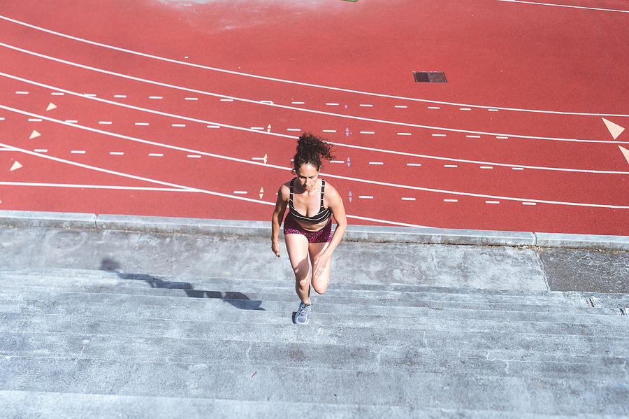 Female athlete cross trains on stadium stairs #1 Photograph by FatCamera