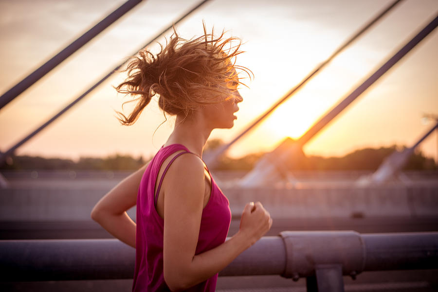 Female athlete running over the bridge in the morning #1 Photograph by Bogdankosanovic