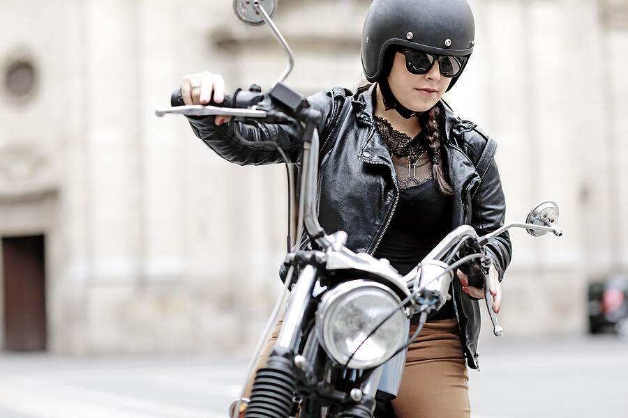 Female motorcyclist preparing for a ride on a vintage motorbike #1 Photograph by Lorado