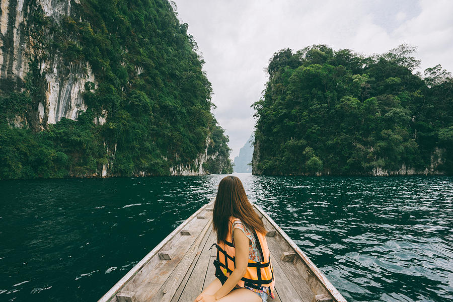 Female tourist exploring lush Jungle lake surrounded by limestone cliffs, Khao Sok National Park, Thailand #1 Photograph by Sam Spicer