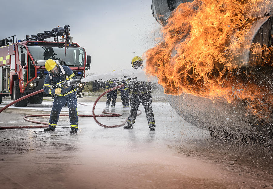 Firemen spraying water on simulated aircraft fire at training facility #1 Photograph by Monty Rakusen