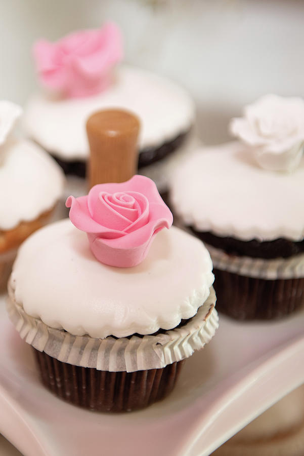 Fresh delicious cupcakes with white sugar garnish and pink sweet flower on top #1 Photograph by Michalakis Ppalis