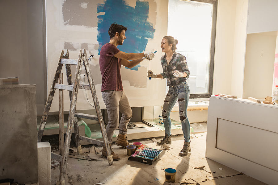 Full length of happy couple having fun while painting their walls. #1 Photograph by Skynesher