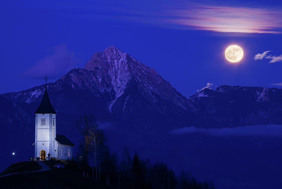 Full moon rising over Jamnik church and Storzic at dusk. #1 Photograph by Ian Middleton